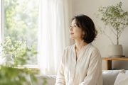 窓辺で外を眺めながら静かに気持ちを整える40代50代女性