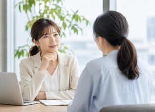 40代の女性同士が明るいオフィスで1on1を行い、対話を通してチームの小さなズレを見直している様子