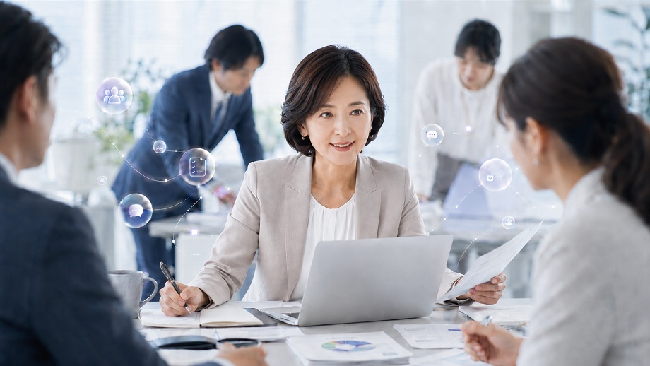 女性管理職の抱え込みをイメージした、職場で周囲と調整しながら業務を進める女性