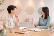 1on1面談で向かい合って話す2人の女性。明るいオフィスで、1人がメモを取りながら対話している様子