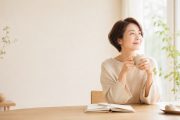 窓辺でカップを手に、穏やかな時間を過ごすアラフィフ女性