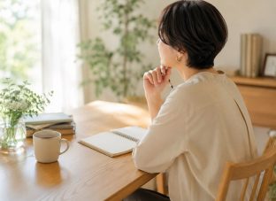 50代からの働き方を見直す女性。明るい部屋のデスクでノートを前に、自分に合う仕事や役割について考えている様子