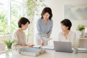 明るいオフィスで資料を囲みながら業務分担について話し合う3人の女性