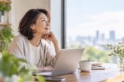 **ALT：** 50代のキャリアやこれからの働き方について、窓辺で考える40代後半の女性