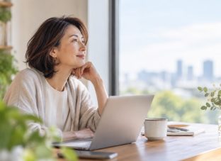 **ALT：** 50代のキャリアやこれからの働き方について、窓辺で考える40代後半の女性