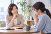 明るいオフィスで、丸テーブルを挟んで向かい合い、穏やかに対話する二人の女性。片方がやさしく話を聴き、もう片方が考え込みながら相談している様子。