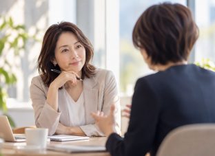明るいオフィスで1on1の対話をする40〜50代の女性たち